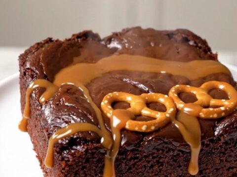 A close-up of a serving of warm chocolate caramel pretzel dump cake on a white plate.
