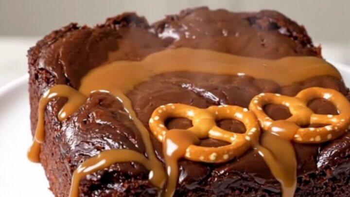 A close-up of a serving of warm chocolate caramel pretzel dump cake on a white plate.