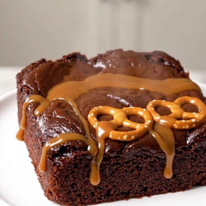 A close-up of a serving of warm chocolate caramel pretzel dump cake on a white plate.