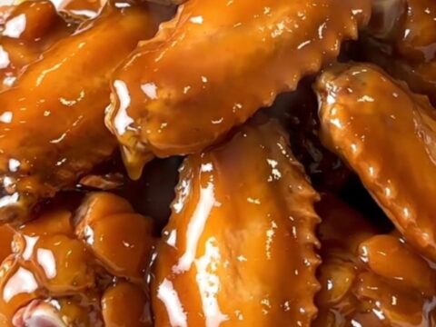A close-up view of glistening, honey-glazed chicken wings in a slow cooker.