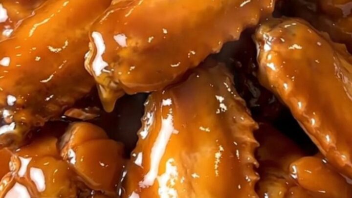 A close-up view of glistening, honey-glazed chicken wings in a slow cooker.