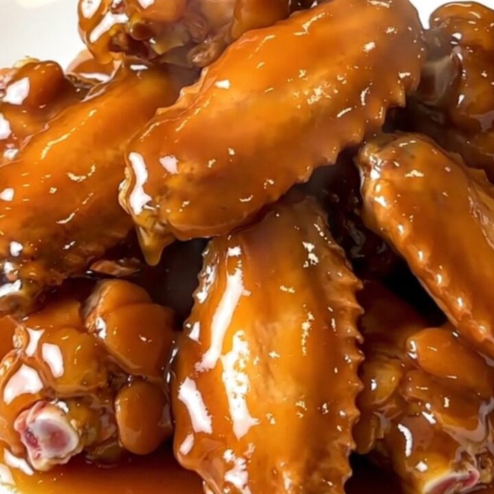 A close-up view of glistening, honey-glazed chicken wings in a slow cooker.