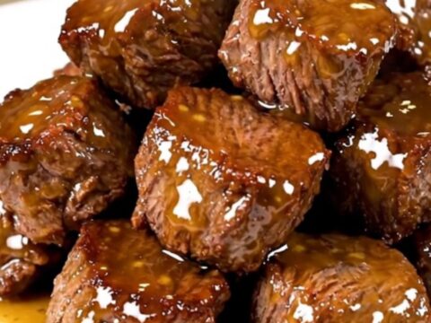 A white plate filled with glossy, glazed honey mustard steak bites with a soft-focus background.