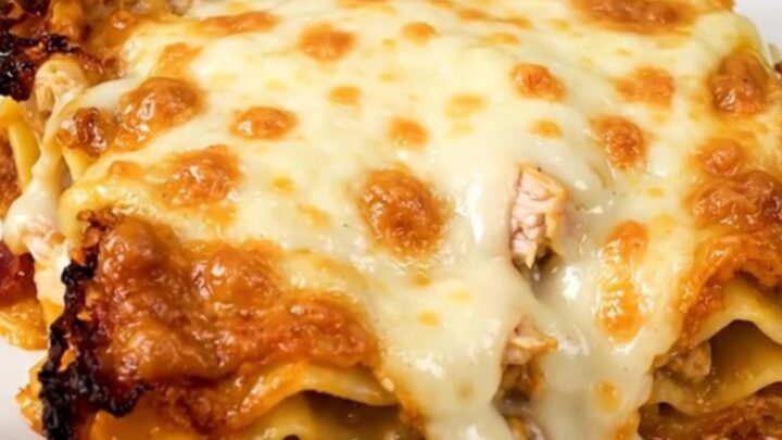 A close-up of a serving of creamy chicken bacon ranch lasagna on a white plate.