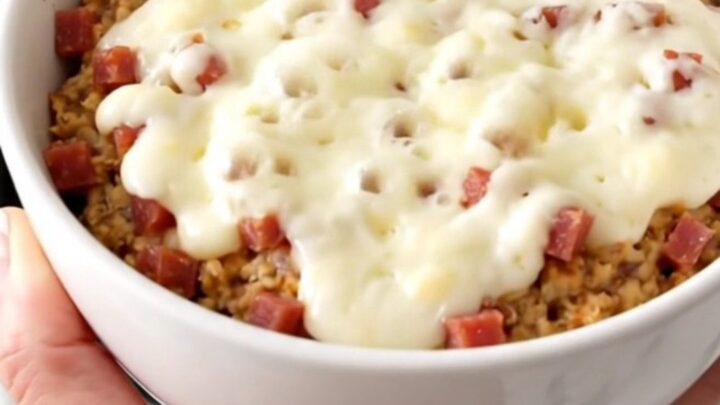 A white bowl filled with creamy, melted pastrami and Swiss cheese dip, showing a rich and glossy texture.