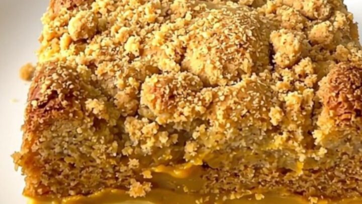 A top-down view of a black slow cooker filled with a creamy pumpkin chai mixture topped with a light layer of cake mix.