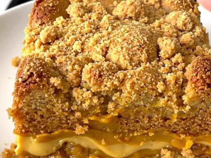 A top-down view of a black slow cooker filled with a creamy pumpkin chai mixture topped with a light layer of cake mix.