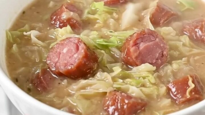 A steaming bowl of creamy kielbasa and cabbage chowder served in a white bowl.