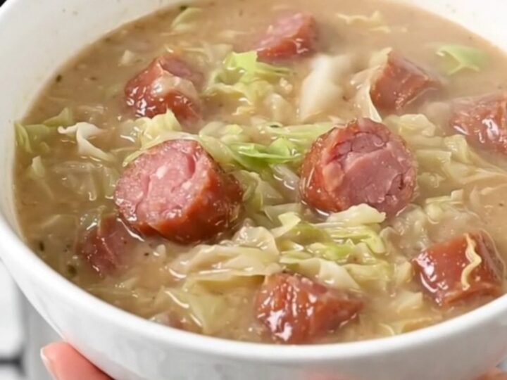 A steaming bowl of creamy kielbasa and cabbage chowder served in a white bowl.