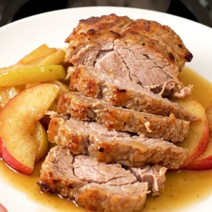 A slow cooker filled with pork tenderloin and sliced apples simmered in a spiced cider glaze.