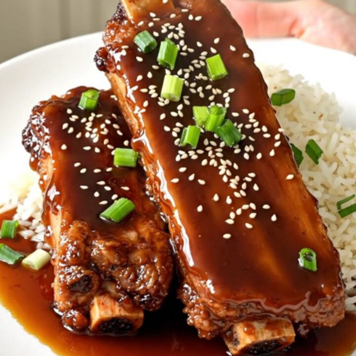 Slow cooker filled with country-style pork ribs glazed in a rich teriyaki and ginger sauce on a quartz countertop.