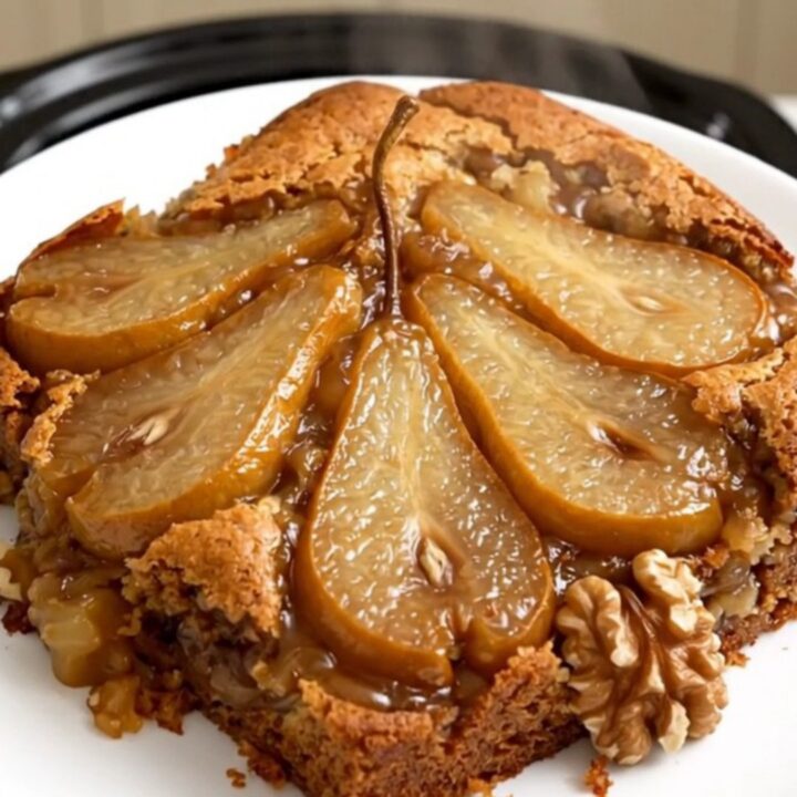 Warm spiced pear and walnut dump cake in a black slow cooker, showcasing a golden, buttery topping.