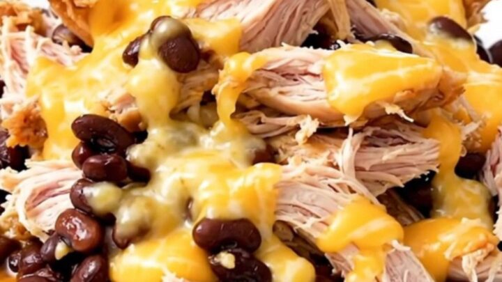 A top-down view of slow cooker chicken with black beans and melted Monterey Jack cheese.