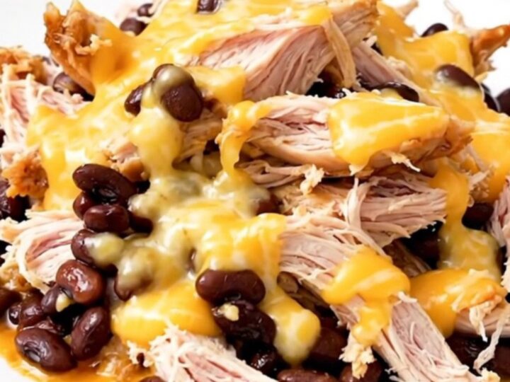 A top-down view of slow cooker chicken with black beans and melted Monterey Jack cheese.