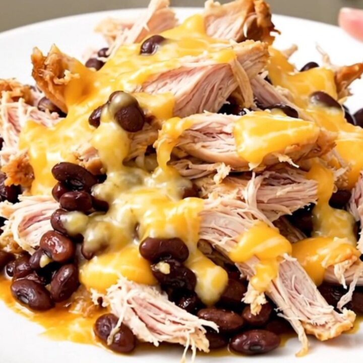 A top-down view of slow cooker chicken with black beans and melted Monterey Jack cheese.