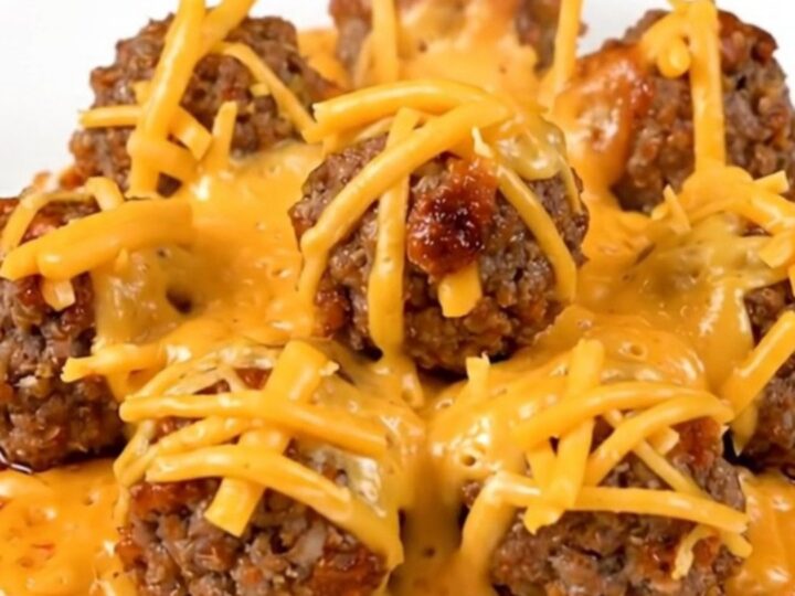 A plate of steaming hot slow cooker cheesy enchilada meatballs covered in melted cheese.