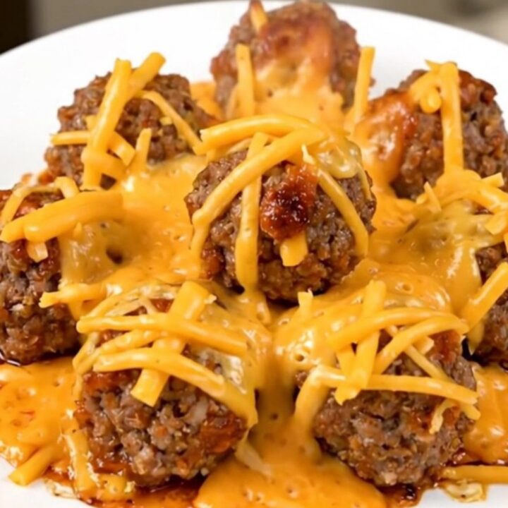 A plate of steaming hot slow cooker cheesy enchilada meatballs covered in melted cheese.