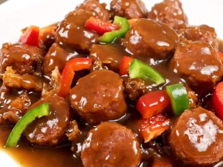 A steaming slow cooker filled with Italian sausage, chopped bell peppers, and a savory broth.