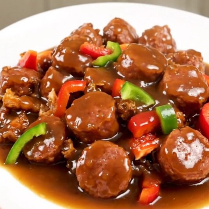 A steaming slow cooker filled with Italian sausage, chopped bell peppers, and a savory broth.