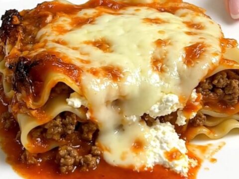 A steaming, hearty serving of ground beef lasagna in a slow cooker on a bright kitchen counter.
