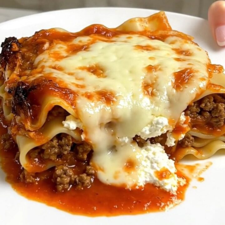 A steaming, hearty serving of ground beef lasagna in a slow cooker on a bright kitchen counter.