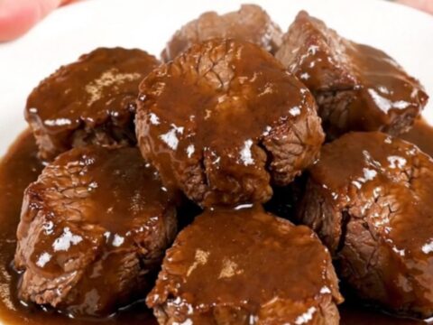 A close-up overhead view of tender, glossy Worcestershire butter steak bites in a slow cooker.