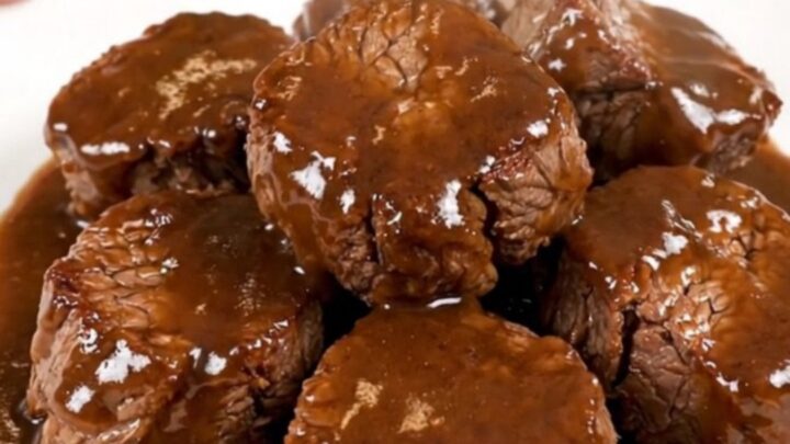 A close-up overhead view of tender, glossy Worcestershire butter steak bites in a slow cooker.
