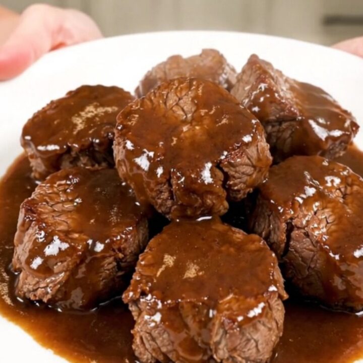 A close-up overhead view of tender, glossy Worcestershire butter steak bites in a slow cooker.
