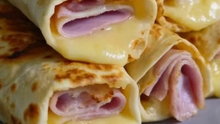 A stack of golden brown air fryer ham and cheese wraps on a white plate.