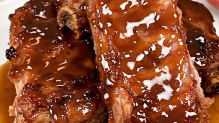 Close-up of tender, glazed maple bourbon country-style ribs on a white plate.