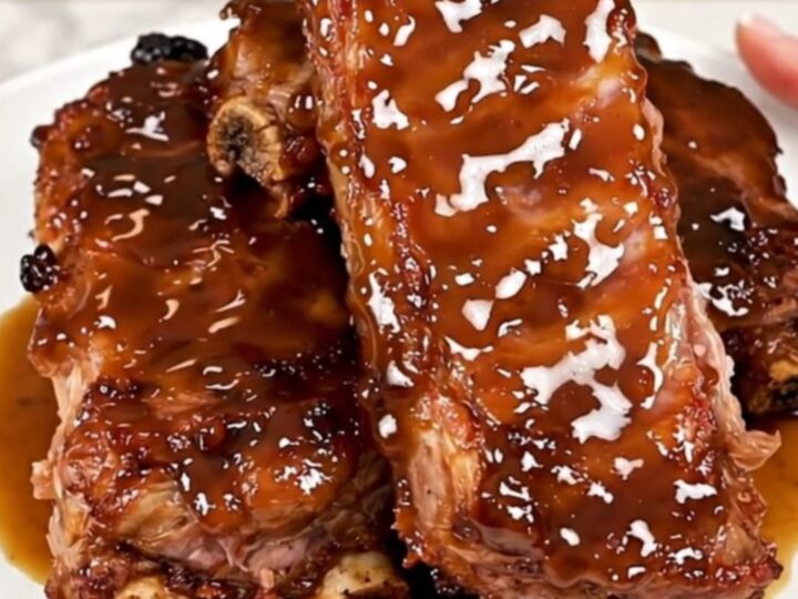 Close-up of tender, glazed maple bourbon country-style ribs on a white plate.