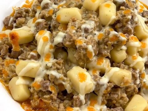 A steaming, creamy beef and gnocchi casserole served on a plain white plate