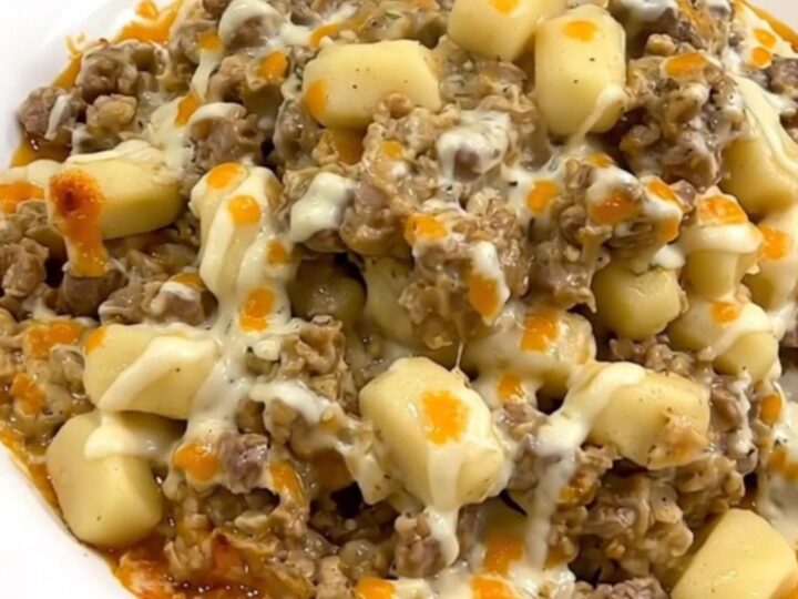 A steaming, creamy beef and gnocchi casserole served on a plain white plate