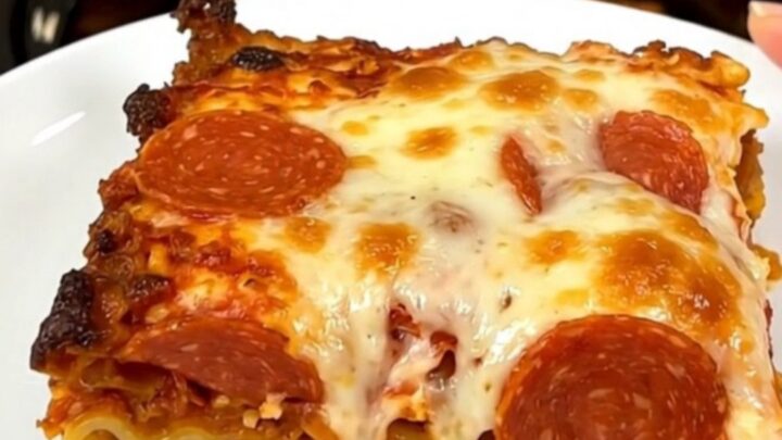 A top-down view of a black slow cooker filled with layers of sausage, pepperoni, and sauce.