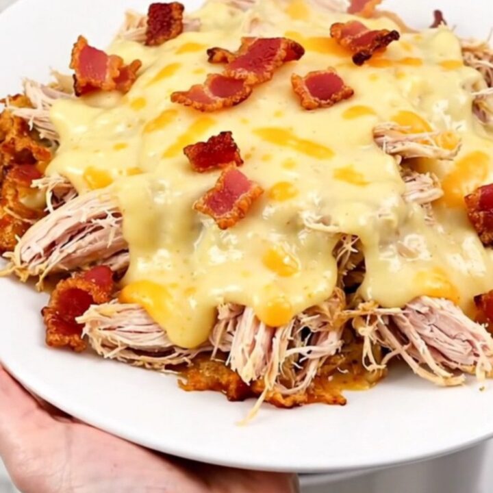 A slow cooker filled with creamy shredded chicken, bacon, and melted muenster cheese.