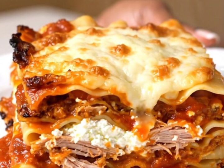 A steaming slice of slow cooker turkey marinara lasagna on a white plate with melted mozzarella.