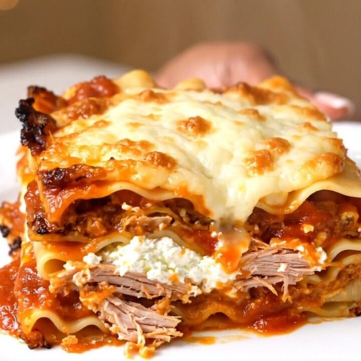 A steaming slice of slow cooker turkey marinara lasagna on a white plate with melted mozzarella.
