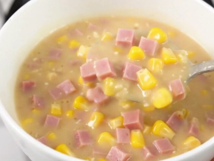A steaming bowl of creamy ham and corn chowder served in a plain white bowl.