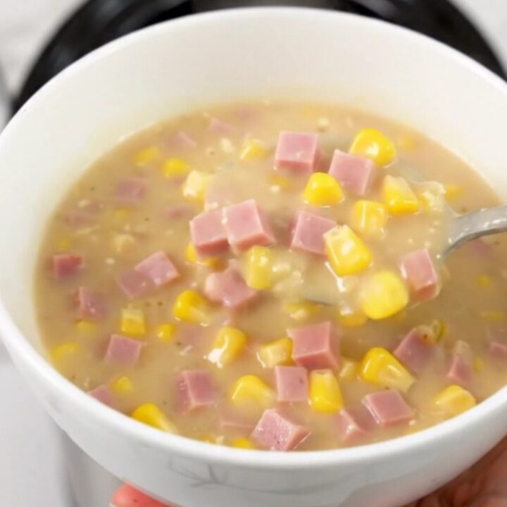 A steaming bowl of creamy ham and corn chowder served in a plain white bowl.