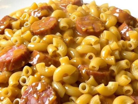A steaming, creamy bowl of macaroni with sliced smoked sausage and taco seasoning.