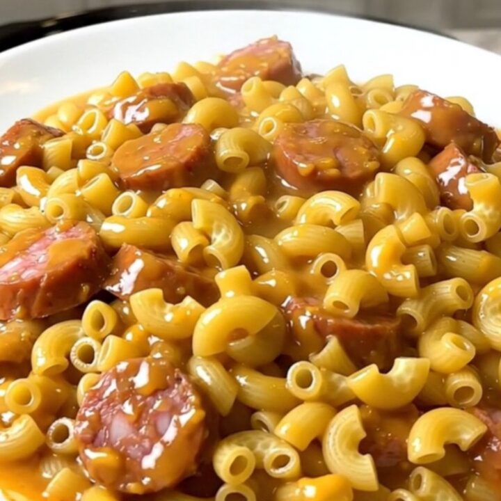 A steaming, creamy bowl of macaroni with sliced smoked sausage and taco seasoning.