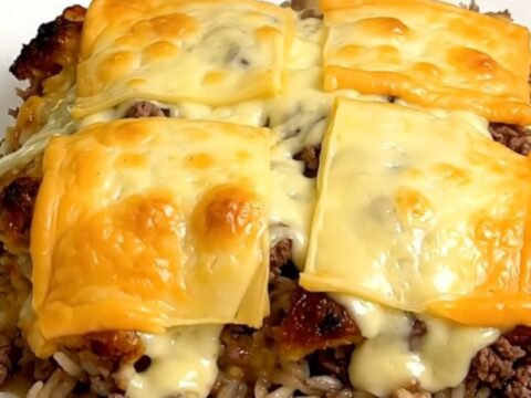 A steaming bowl of French onion ground beef and rice casserole topped with melted Swiss cheese.
