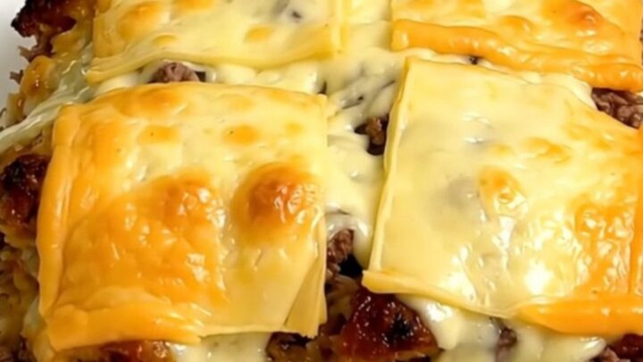A steaming bowl of French onion ground beef and rice casserole topped with melted Swiss cheese.