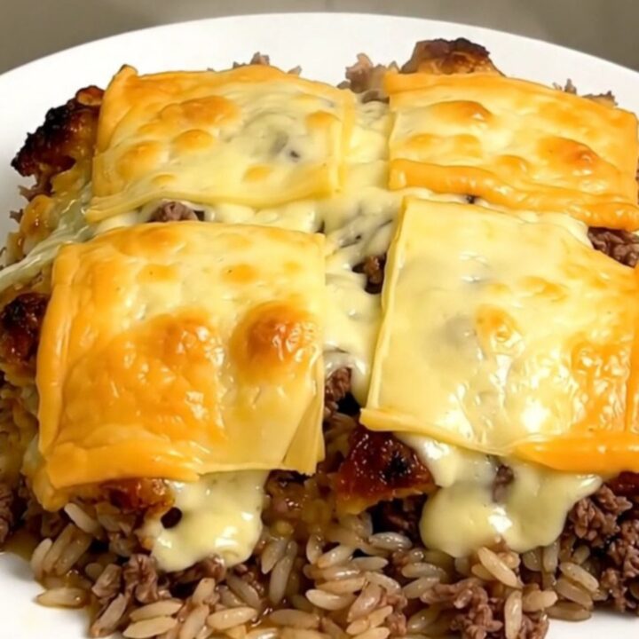 A steaming bowl of French onion ground beef and rice casserole topped with melted Swiss cheese.