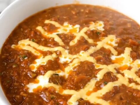 A white bowl filled with creamy cheesy turkey chili, steaming and garnished with a hint of cilantro.