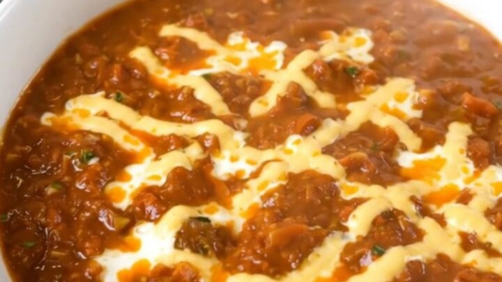 A white bowl filled with creamy cheesy turkey chili, steaming and garnished with a hint of cilantro.