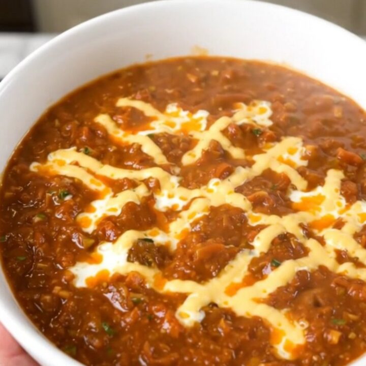 A white bowl filled with creamy cheesy turkey chili, steaming and garnished with a hint of cilantro.