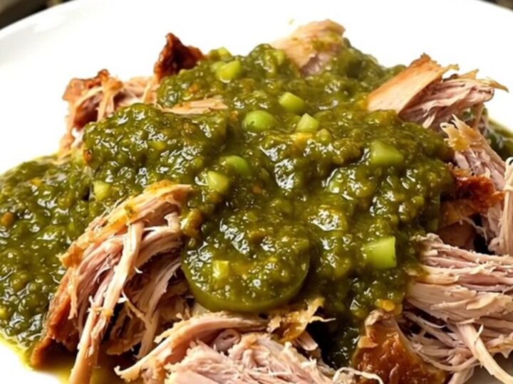 A top-down view of a slow cooker filled with raw turkey tenderloins, diced onions, and salsa verde.