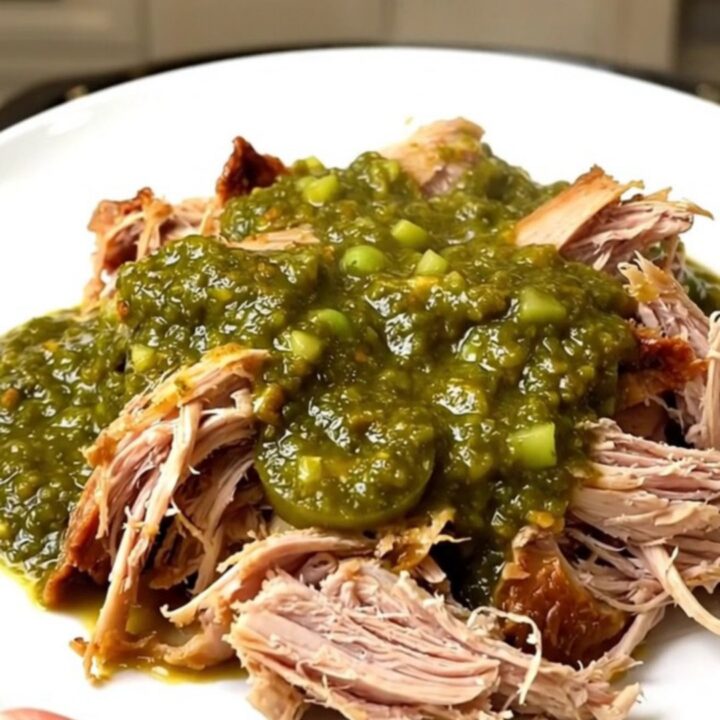 A top-down view of a slow cooker filled with raw turkey tenderloins, diced onions, and salsa verde.
