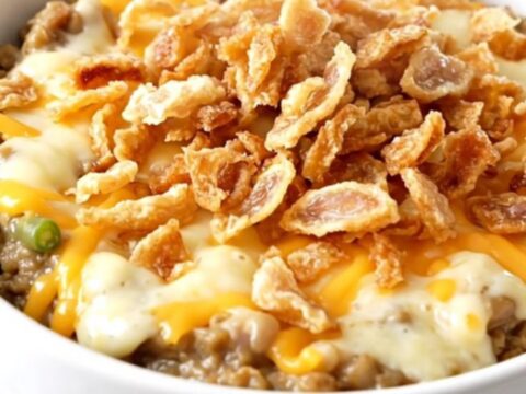 A top-down view of a black slow cooker filled with a creamy green bean and cheese mixture.